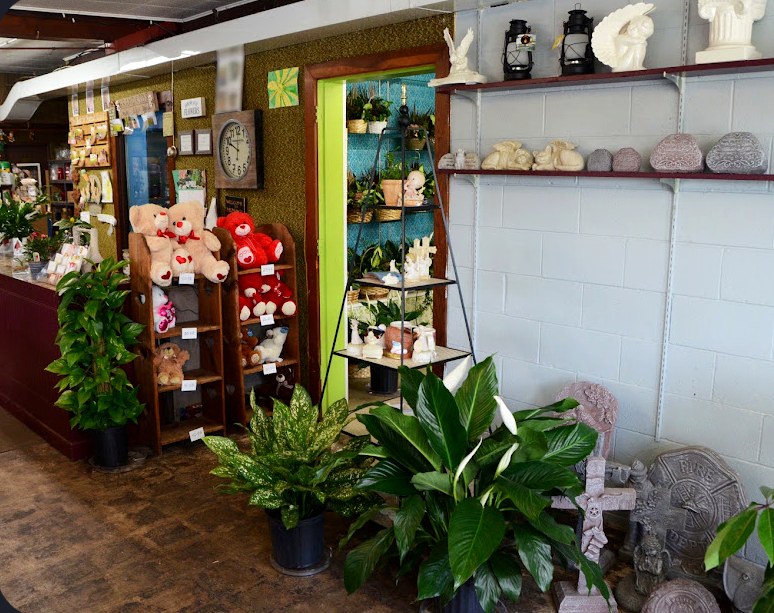 Inside Flowers By Mary Jane, with shelves of teddy bears, green plants, and garden statuary